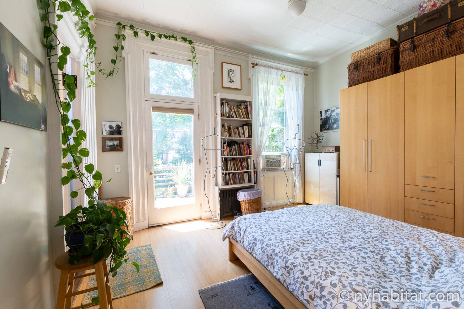 Immagine di camera da letto in NY-17602 con letto queen size, ripiano per libri, piante, armadio, opera d’arte e porta su una terrazza esterna.