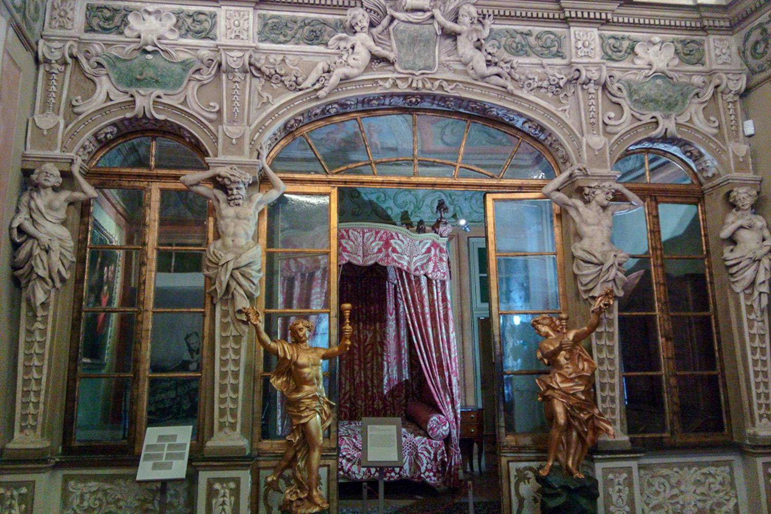 Immagine della facciata di una stanza nel Palazzo Lascaris decorato con sculture di Cherubini e dettagli d’oro.
