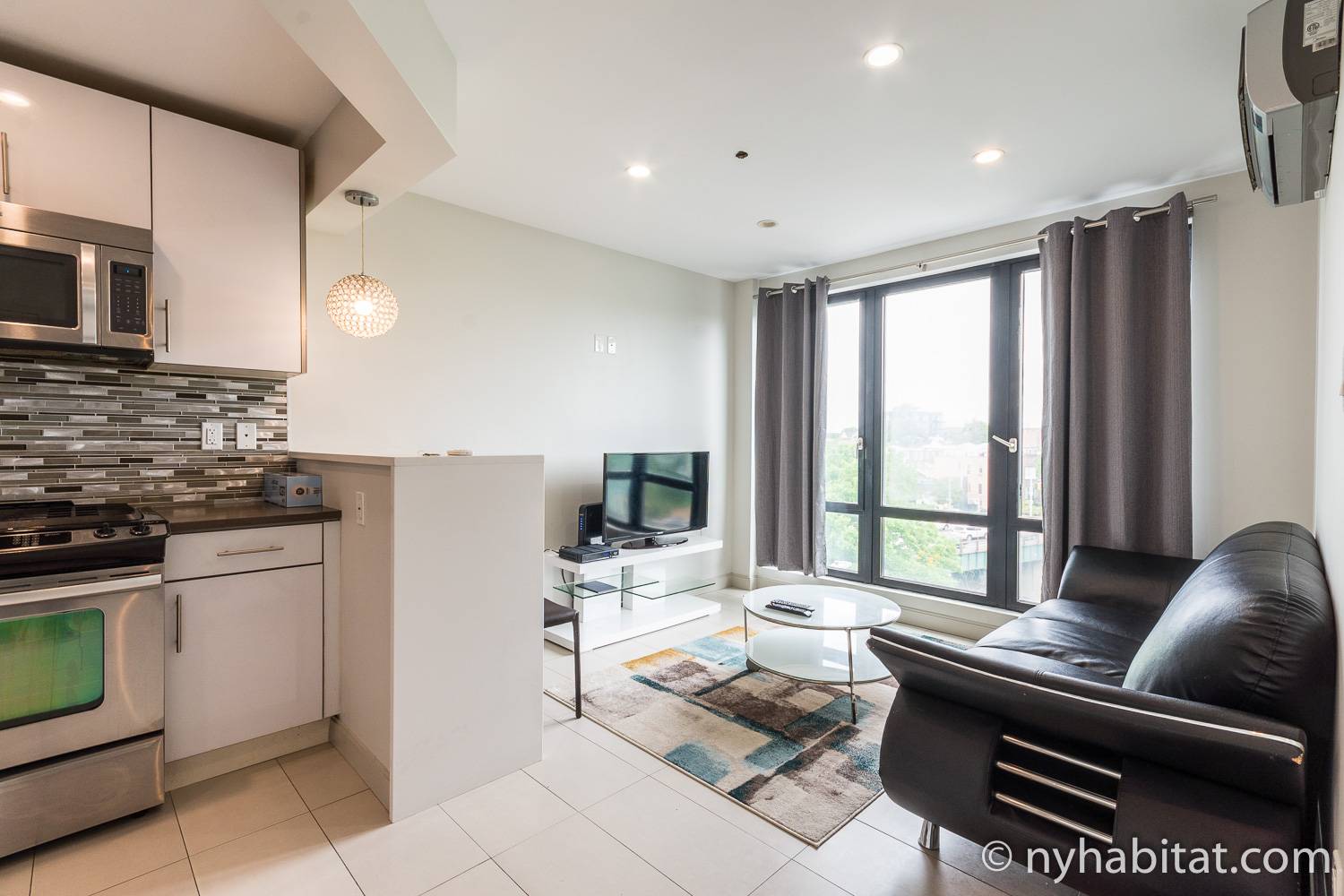 Immagine di un centro abitato di NY-17564 con cucina a vista, divano e televisore.
