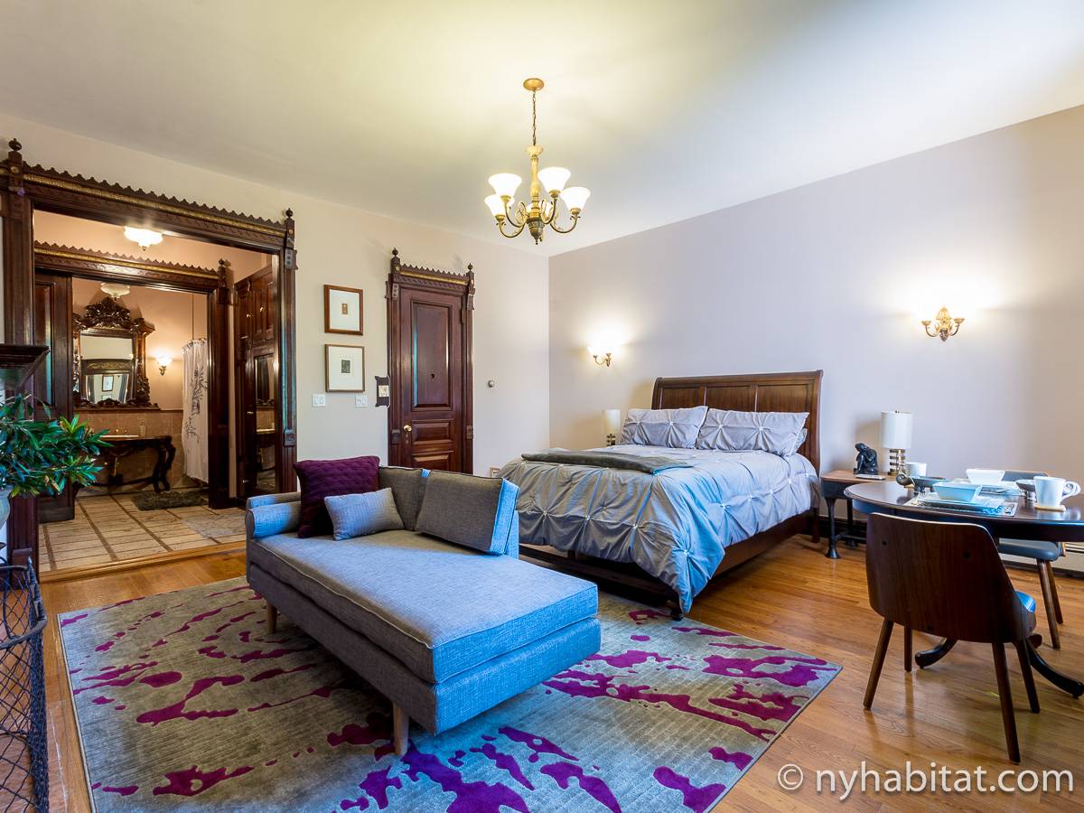 Foto della camera da letto della casa vacanza monolocale NY-17657 ad Harlem con letto e salottino con mobili antichi e legno decorato sullo sfondo