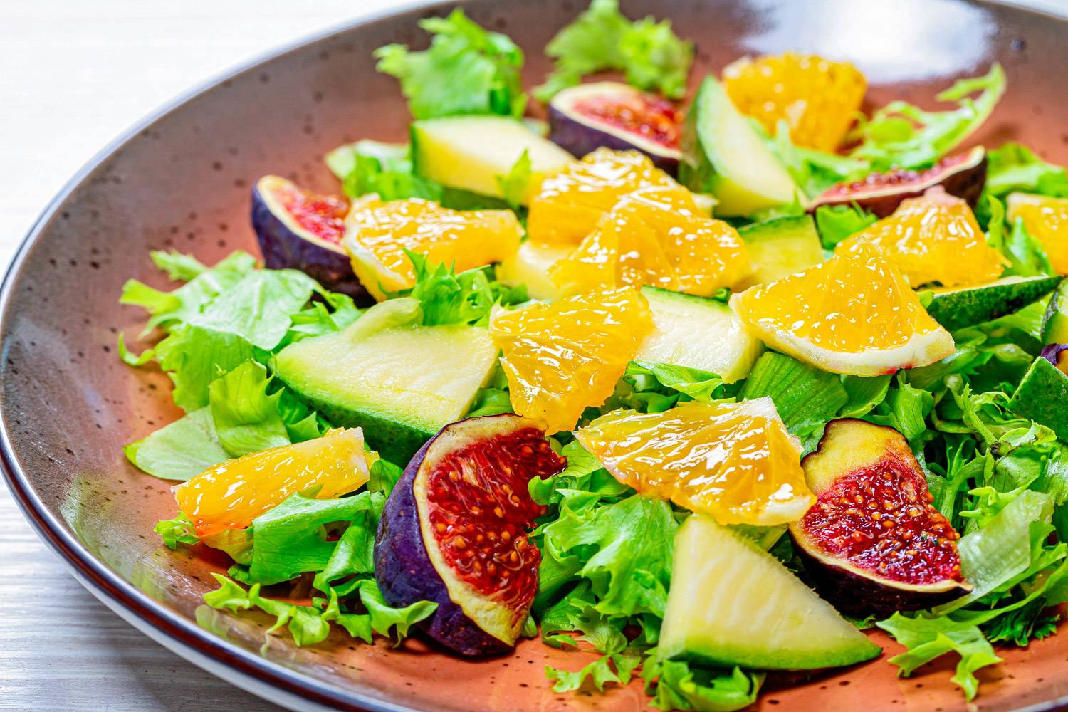 Foto di un’insalata con lattuga, avocado, spicchi di mandarino e fichi