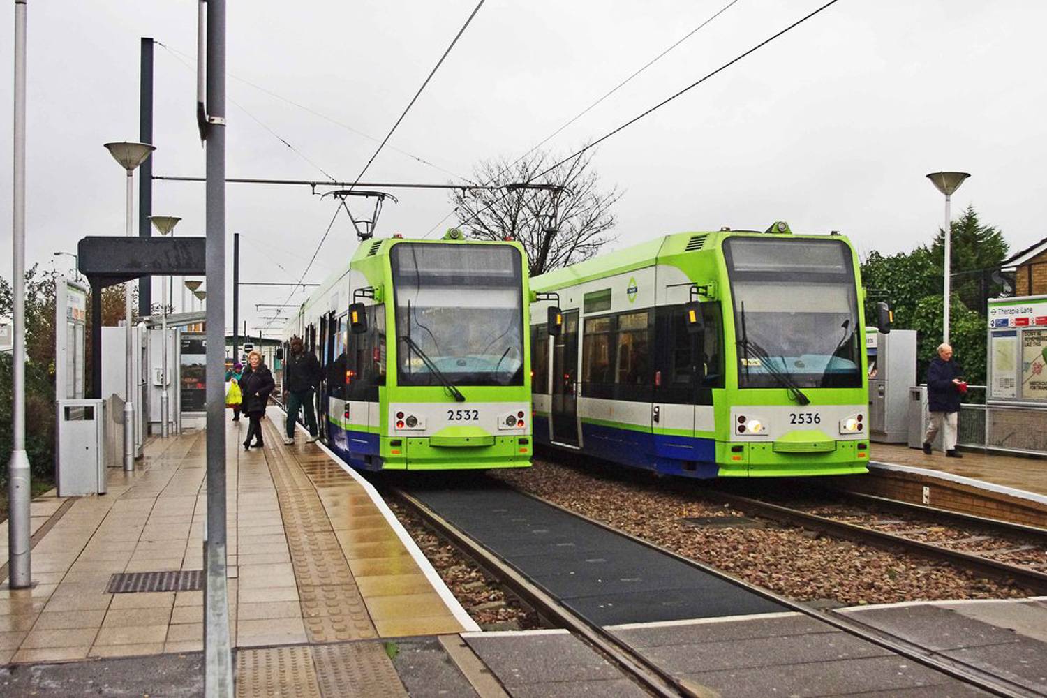 Immagine di due tram londinesi verdi in una stazione.
