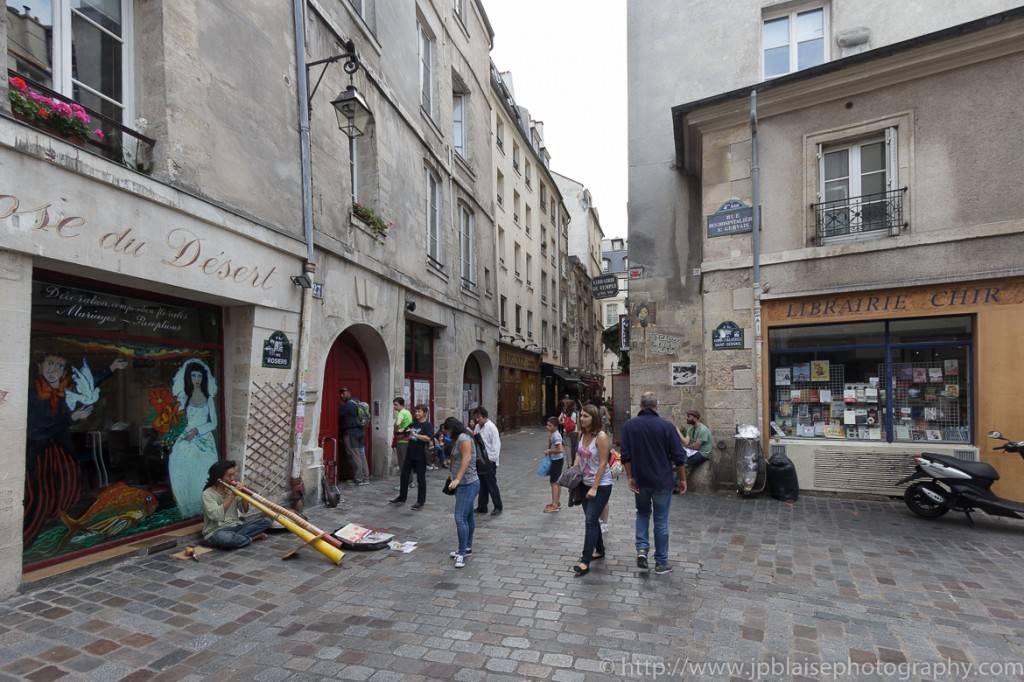 Imagen de un músico tocando para los turistas en una calle adoquinada de Le Marais (París).