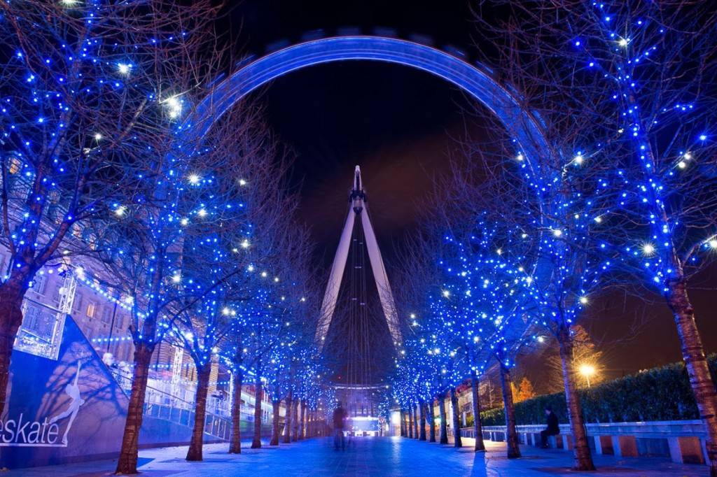 Imagen del Ojo de Londres en frente de árboles adornados con luces navideñas azules