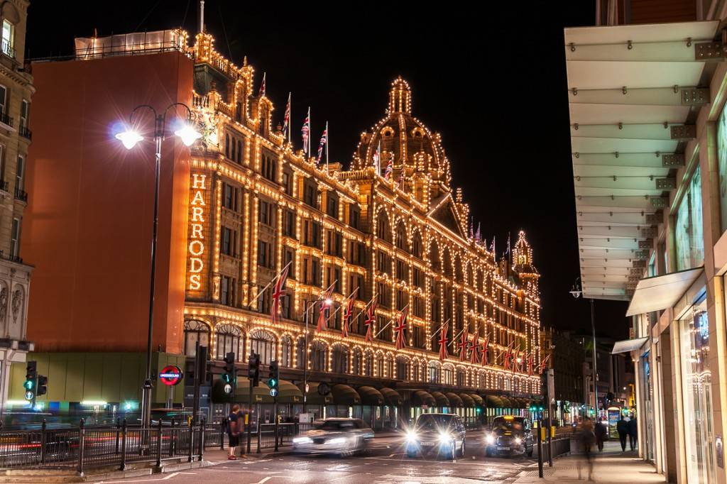 Imagen de los grandes almacenes Harrods frente a una calle con tráfico durante la noche, decorado con luces y adornos navideños