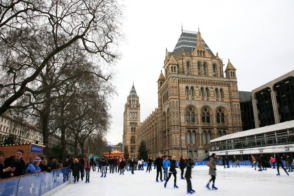 Imagen de un grupo de gente patinando sobre hielo en una pista de patinaje al lado del Museo de Historia Natural de Londres