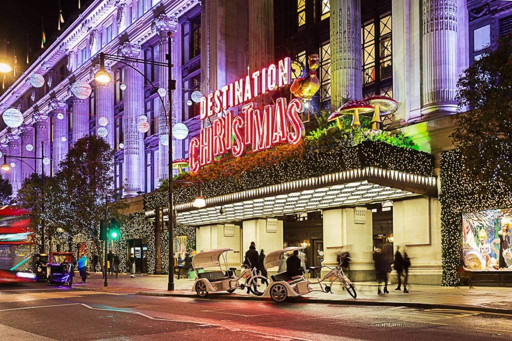 Imagen de un edificio en Oxford Street adornado con luces de Navidad y una gran señal roja con el mensaje «DESTINO: NAVIDAD» rodeado de arbustos y árboles