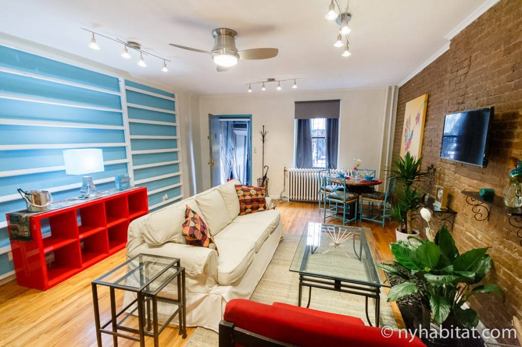 Imagen del colorido salón y del muro de ladrillo del apartamento.