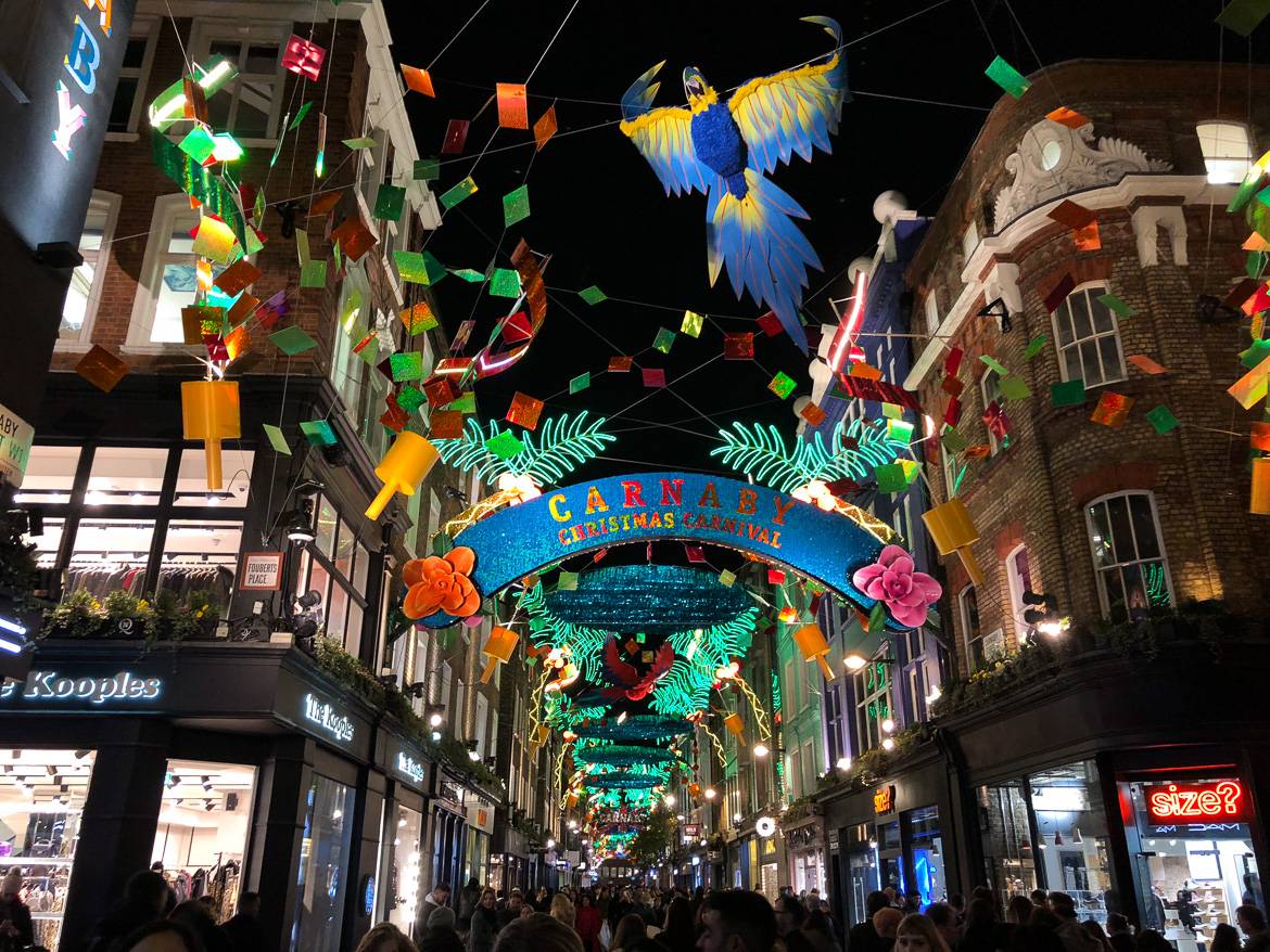 Imagen de Carnaby Street con un colorido alumbrado navideño y personas recorriendo las calles empedradas.