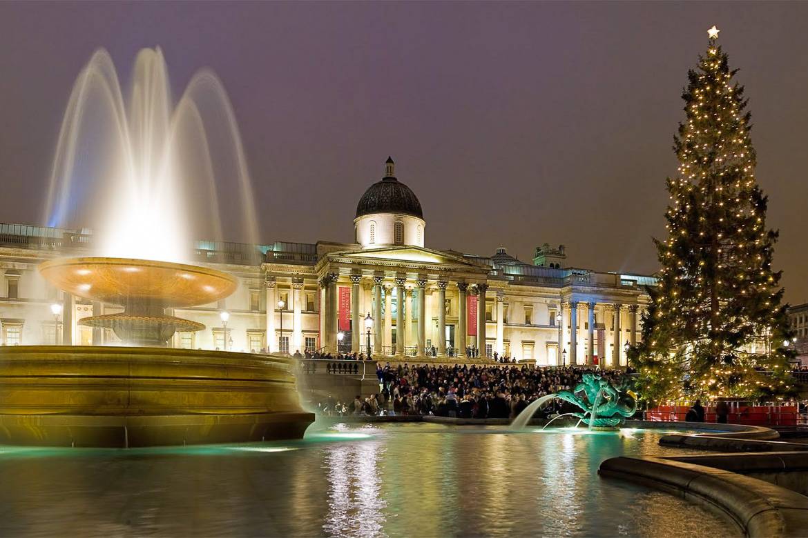 Imagen de un árbol de Navidad junto a una fuente y un gran edificio