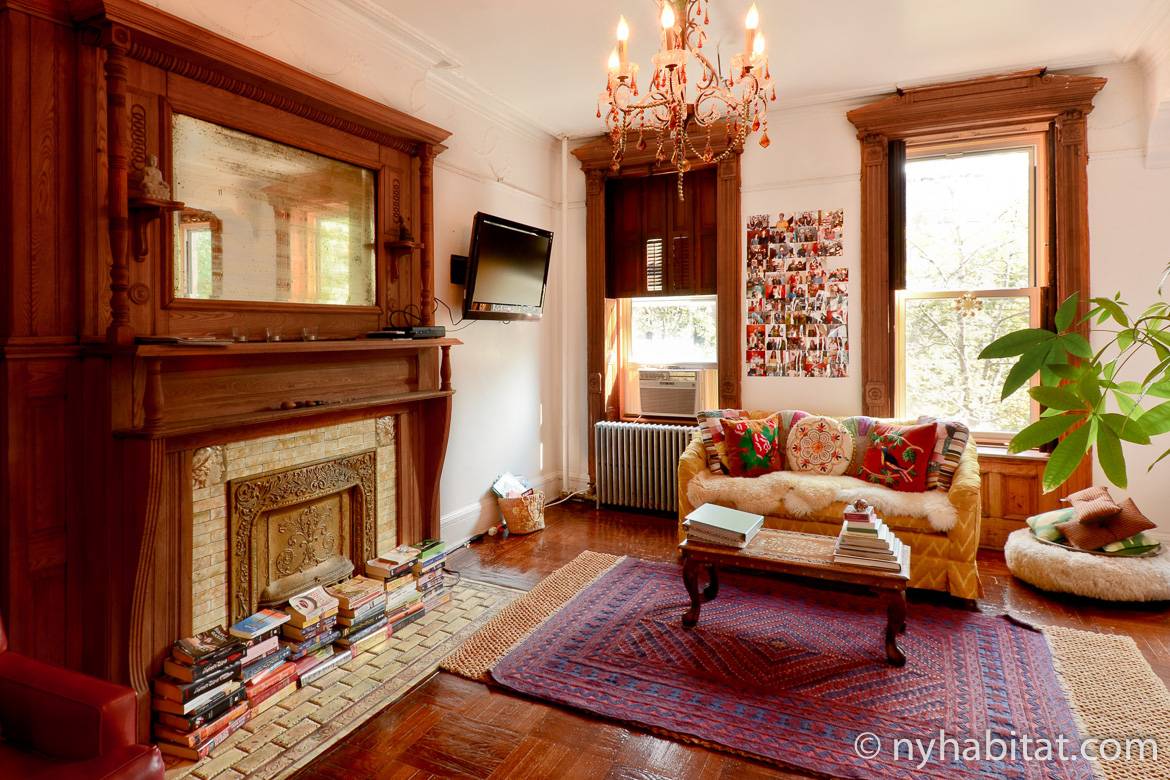 Imagen del salón del NY-14321 con una chimenea y un sofá con cojines decorativos.