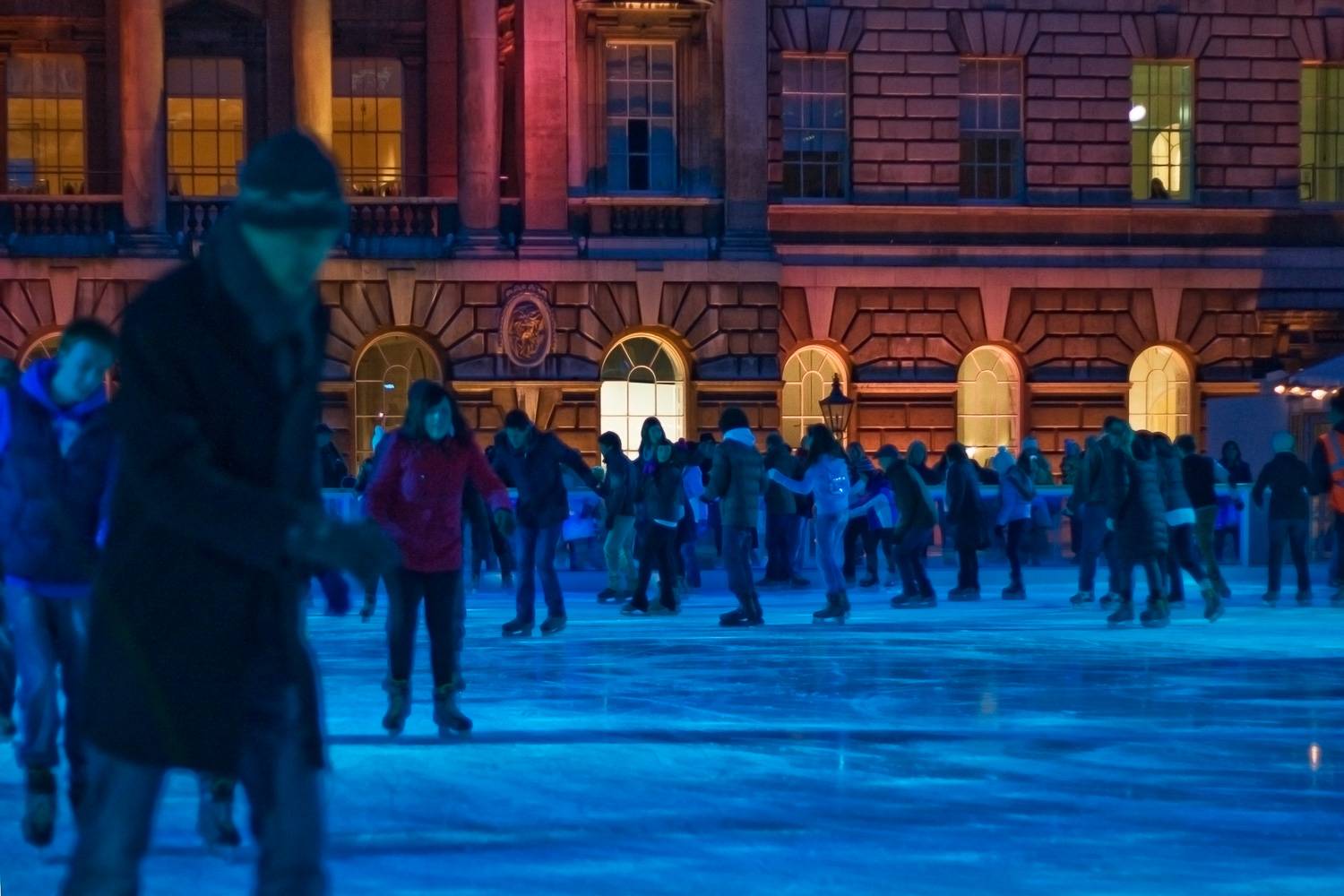 Imagen de gente patinando sobre hielo en la pista de Somerset House en Londres por la noche.