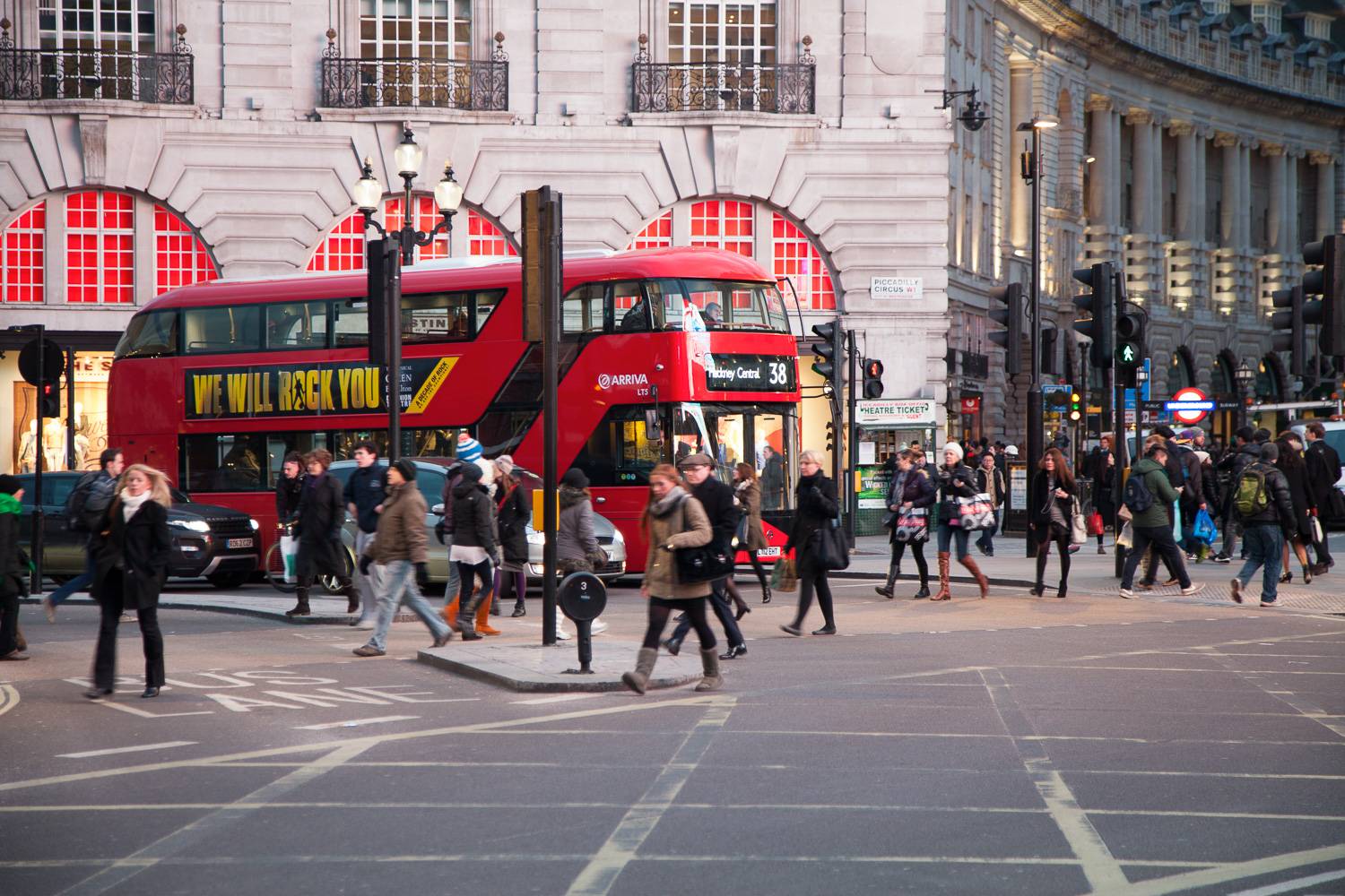 Imagen de peatones y un autobús rojo de dos pisos en las calles de Piccadilly Circus.