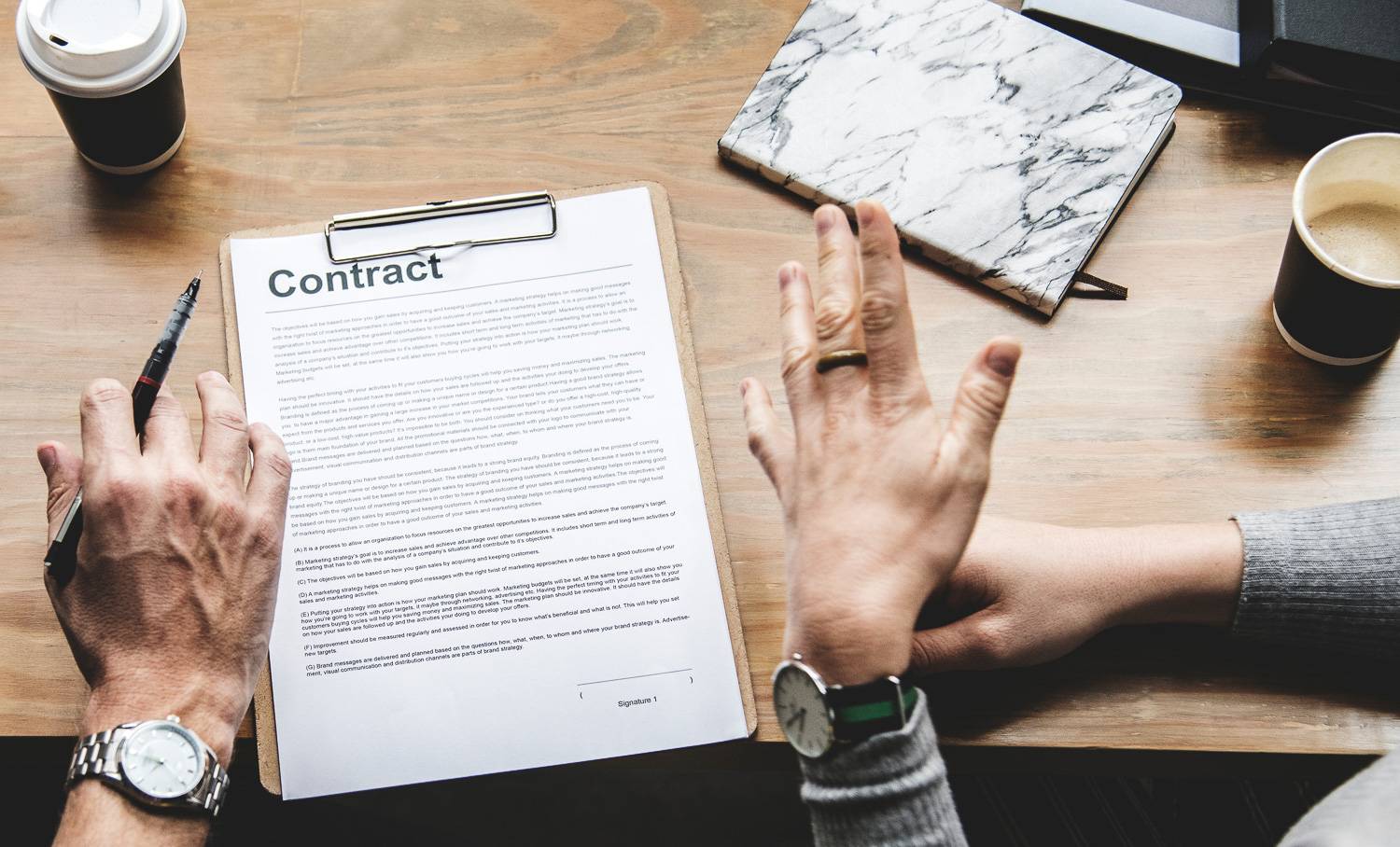 Imagen de las manos de dos personas en mitad de una discusión acerca de un contrato de alquiler.