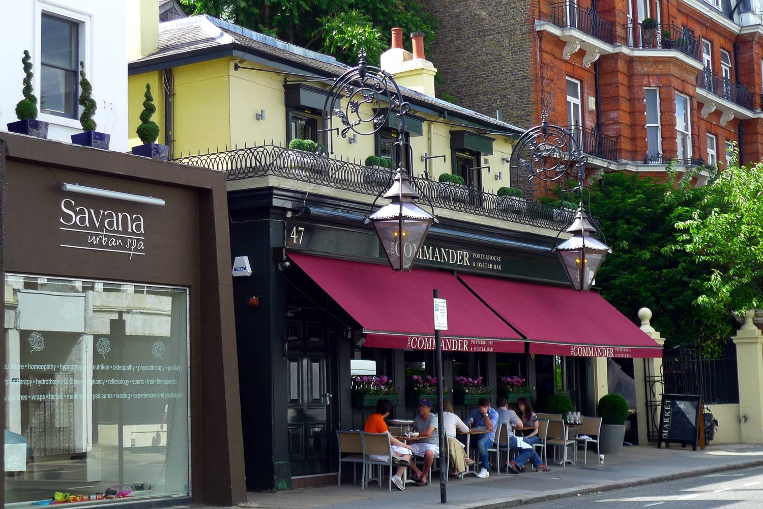Imagen de gente sentada al aire libre en frente de un pub de un barrio de Londres.