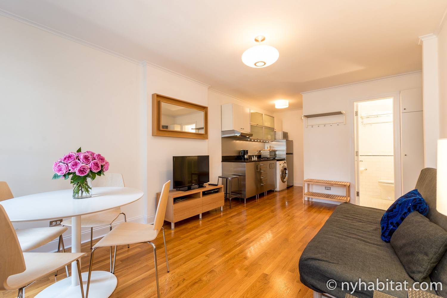 Imagen del salón del NY-5193 con sofá, televisión, mesa, sillas y cocina.