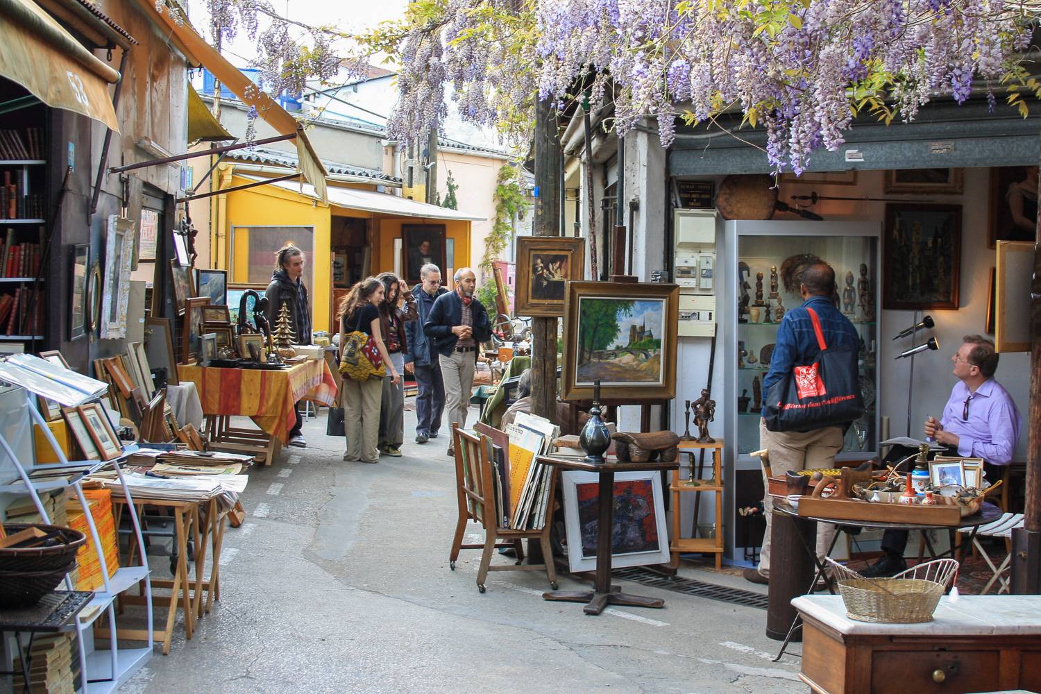 Imagen de personas caminando entre los puestos de antigüedades del mercadillo de Puces de Saint-Ouen.