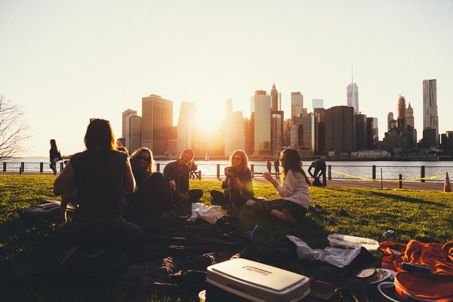 Imagen de un grupo de amigos sentados en el césped admirando las vistas y puesta de sol de Nueva York.